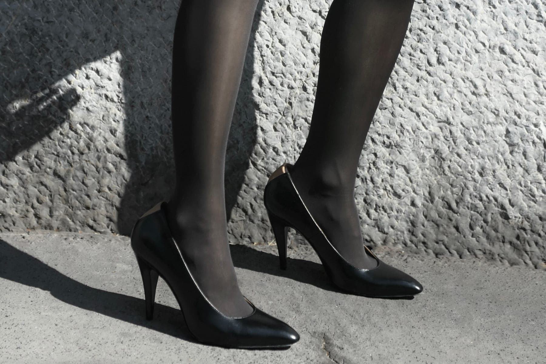 Black heels against a textured stone wall